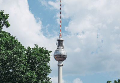 Low angle view of communications tower against cloudy sky