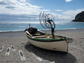 Boat moored on beach against sky