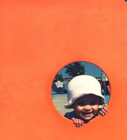 Close-up of happy girl looking through hole of playhouse