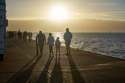 People on beach against sky during sunset