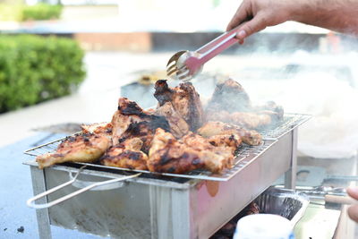 Close-up of person preparing food on barbecue grill