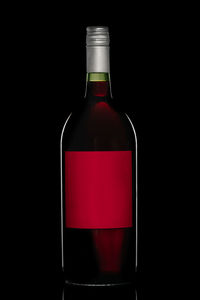 Close-up of red wine bottle against black background