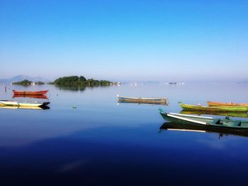 Boats moored in marina against clear blue sky