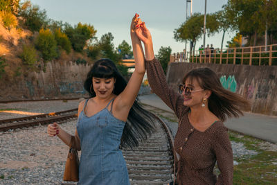 Friends dancing while standing on railroad track