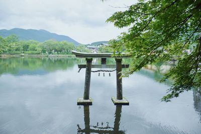 Wooden post in lake against sky