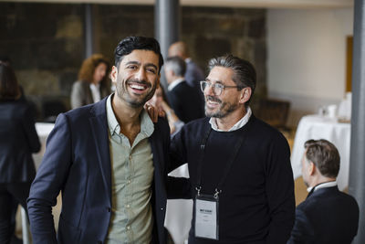 Portrait of happy businessman with male delegate at seminar in convention center