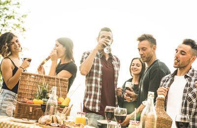 Friends having food and drinks at table against clear sky during party