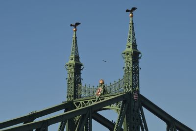 Low angle view of rollercoaster against clear blue sky