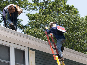 Low angle view of people on built structure against trees
