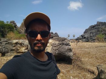 Portrait of young man wearing sunglasses against rock