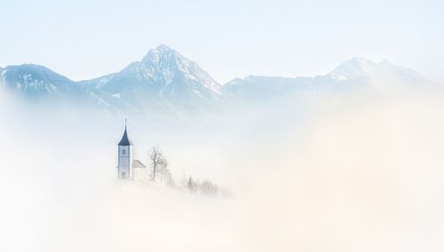 Church amidst fog against mountains