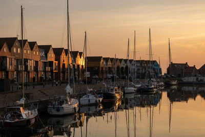 Sailboats moored at harbor during sunset