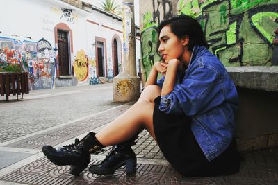 Side view of young woman sitting in city