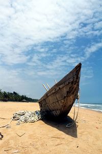 Boat moored on beach against sky