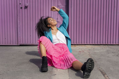 Full length of a smiling woman sitting on wall