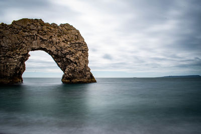 Rock formation in sea against sky