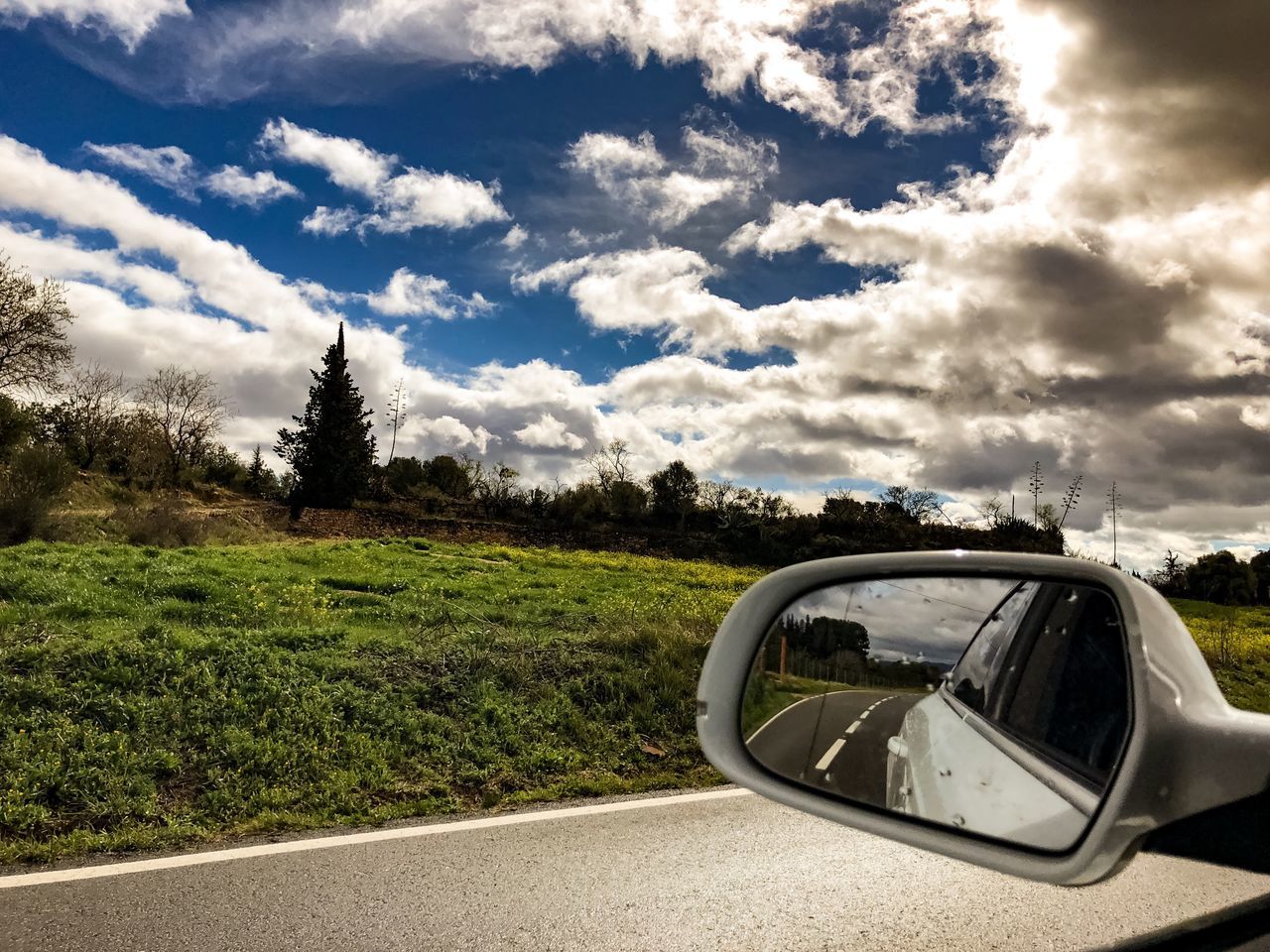 SIDE-VIEW MIRROR OF CAR ON ROAD