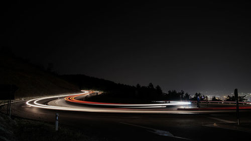 Light trails on road against sky at night