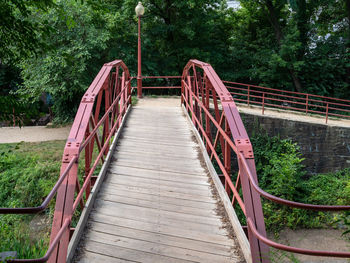 Empty footbridge along trees in forest