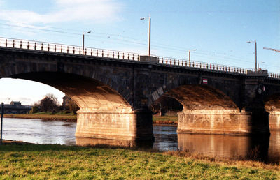 Bridge over river in city against sky