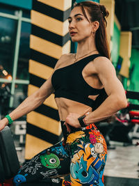 Portrait of young woman standing against wall