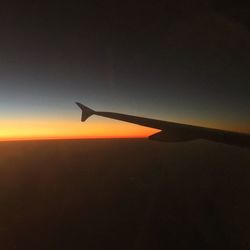 Airplane flying in sky at sunset