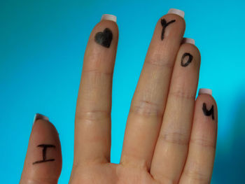 Close-up of woman hand against blue background