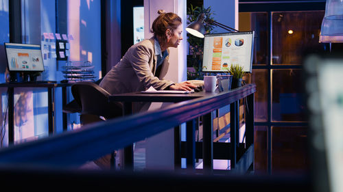 Side view of woman using mobile phone in office