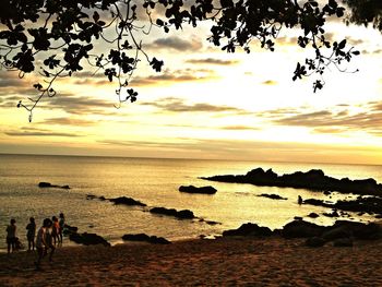 Silhouette people on beach against sky during sunset