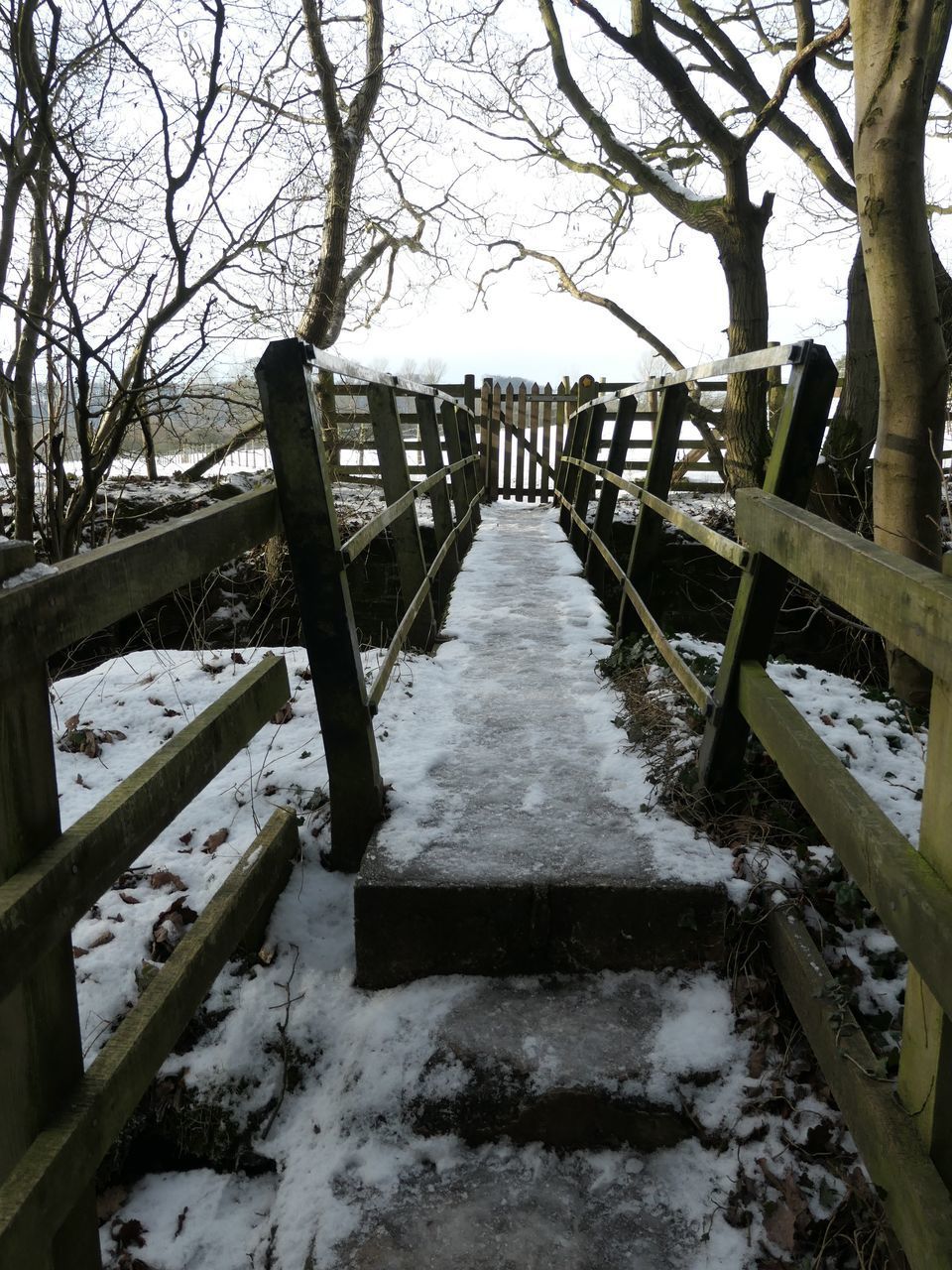 FOOTBRIDGE OVER SNOW COVERED FIELD