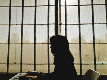 Close-up of silhouette woman against window