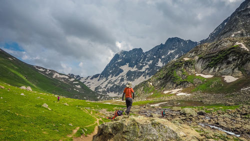 Rear view of man standing on mountain against sky