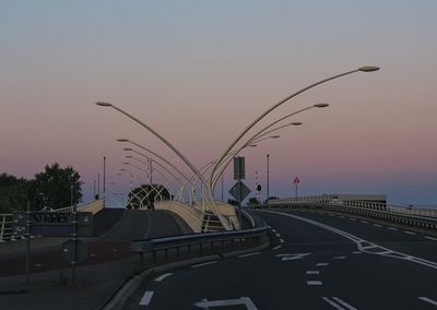 Vehicles on road against sky during sunset