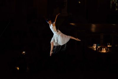 Midsection of woman dancing against black background