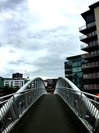 Footbridge in city against sky