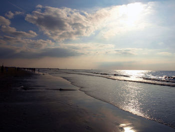 View of calm beach against cloudy sky