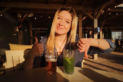 Portrait of woman drinking glass on table at restaurant