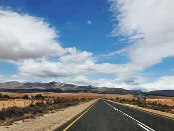 Road leading towards mountains against sky