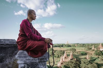 Low angle view of woman sitting against sky