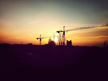 Silhouette of crane against sky at sunset