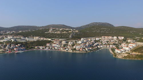 Aerial view of townscape by sea against clear sky