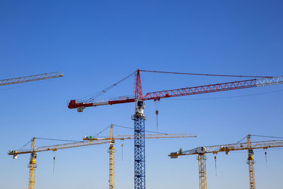 Germany, bavaria, munich, construction cranes against blue sky