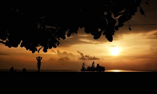 Silhouette people on beach against sky during sunset