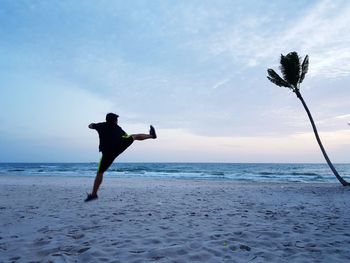 Rear view of man standing on beach against sky