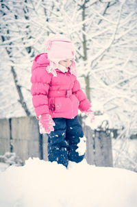 Girl wearing pink warm clothing playing in snow