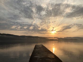 Pier over lake against sky during sunset