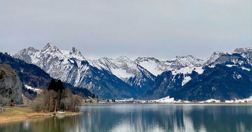 Scenic view of lake by snowcapped mountains against sky