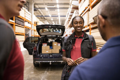 Smiling female sales staff talking with customer in warehouse
