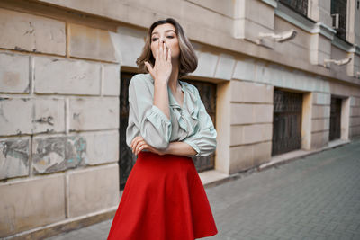 Young woman looking away while standing against brick wall