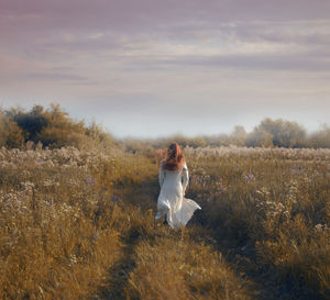 Woman standing on field against sky